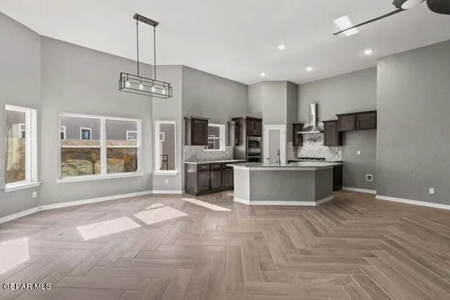 a large kitchen with stainless steel appliances a large counter top a sink and a chandelier