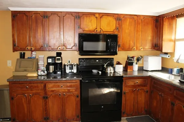 a kitchen with granite countertop a sink stove and microwave