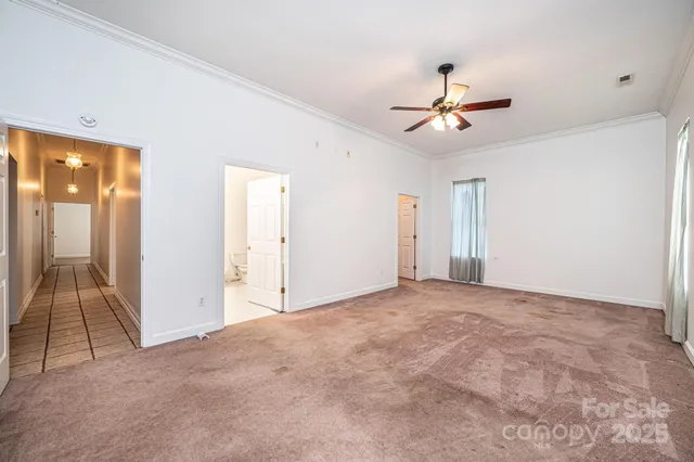 an empty room with chandelier fan and windows