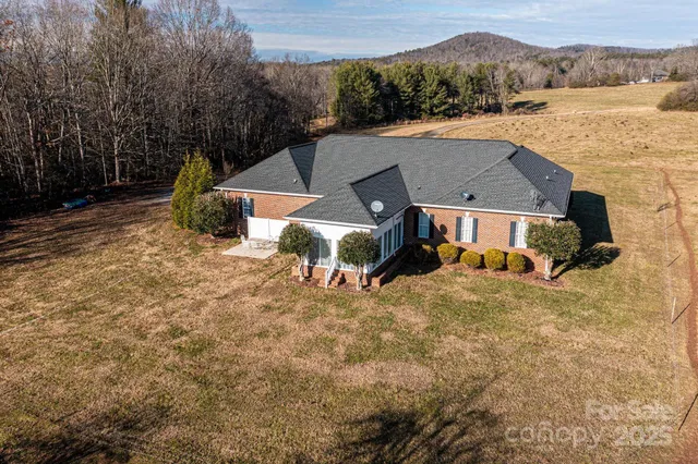 an aerial view of a house with a yard and a large tree