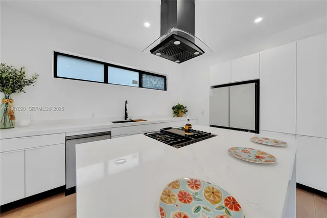 a kitchen with stainless steel appliances a stove a white cabinets and a wooden floor