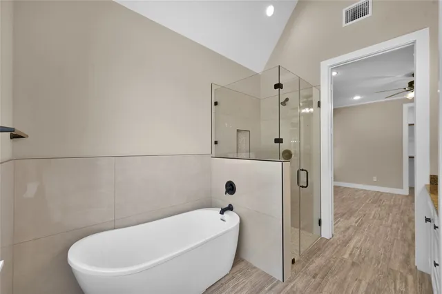 a bathroom with a tub a window and a glass door shower