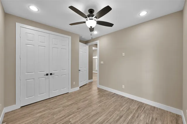 an empty room with wooden floor and ceiling fan