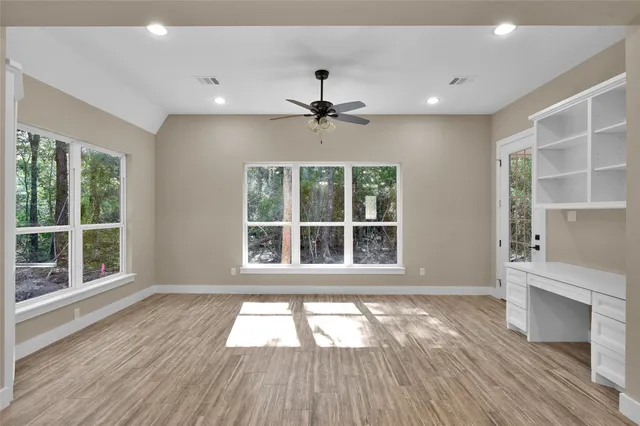 a view of an empty room with a window and wooden floor