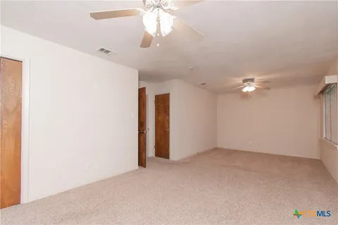 an empty room with a ceiling fan and a window