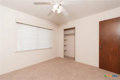 an empty room with a ceiling fan and a window