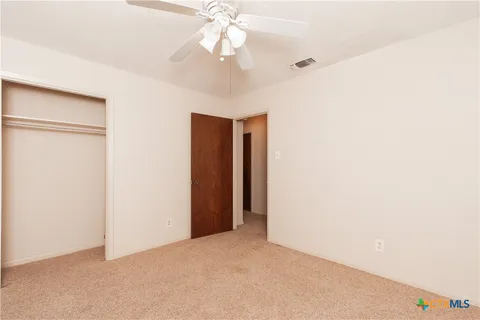 a view of an empty room with a chandelier fan
