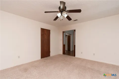 an empty room with closet and a ceiling fan