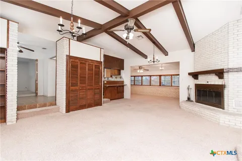a view of an empty room with a fireplace and chandelier