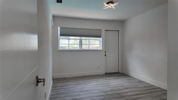 an empty room with a window and wooden floor