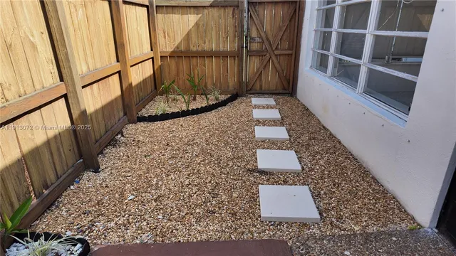 a backyard of a house with plants and palm tree