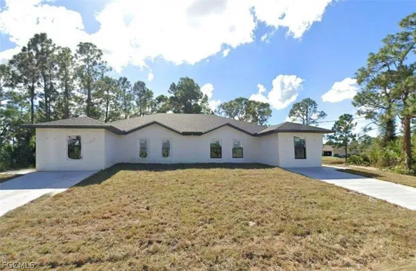 a front view of house with yard and trees in the background