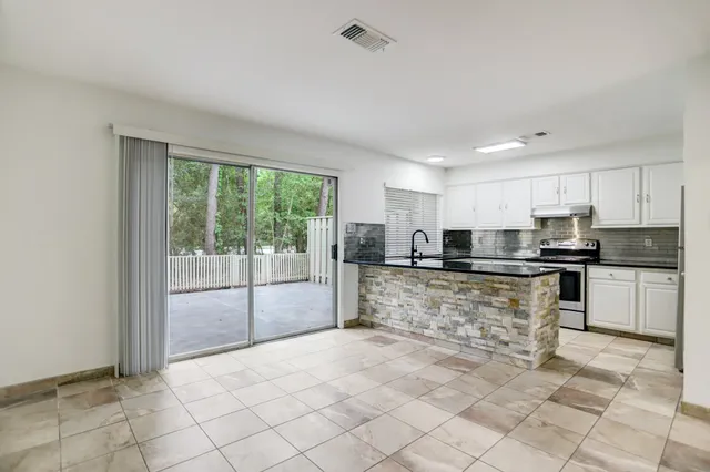 a large kitchen with kitchen island a sink a counter top stainless steel appliances cabinets and a window