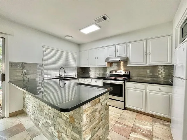 a kitchen with stainless steel appliances granite countertop a sink a stove and cabinets