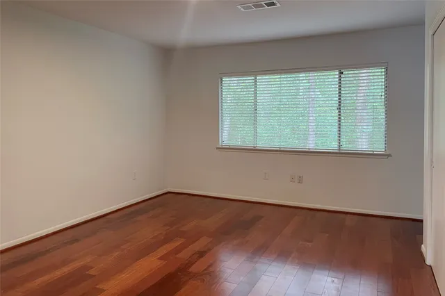 an empty room with wooden floor and a window