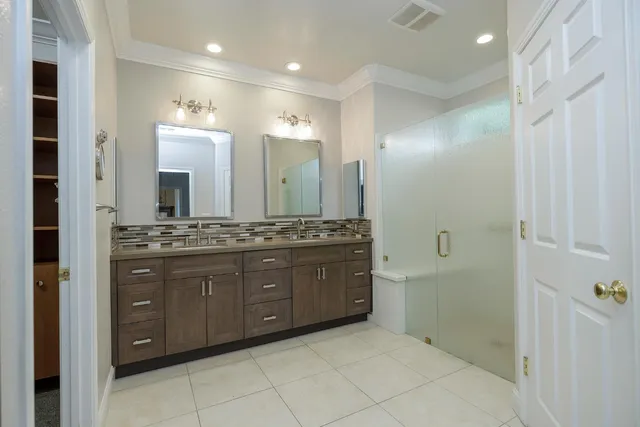 a bathroom with a granite countertop double vanity sink and mirror