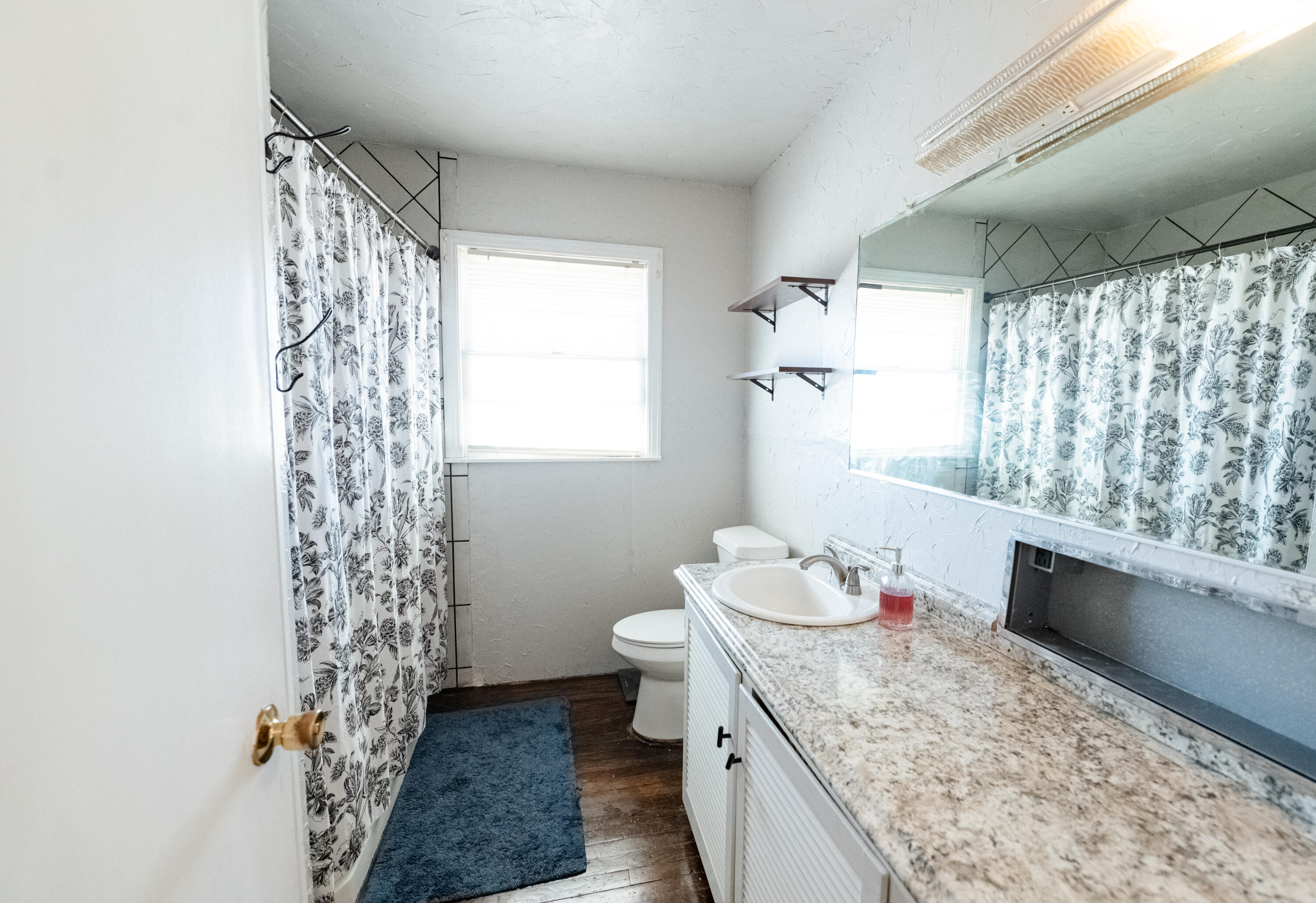 520 East 12th Street Littlefield, TX 79339 - Photo 9 of 17 a bathroom with a granite countertop sink a toilet and shower curtain