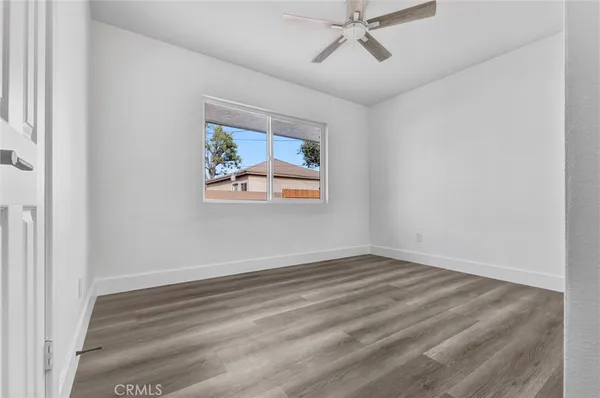 an empty room with wooden floor fan and windows