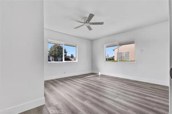 an empty room with wooden floor window and ceiling fan