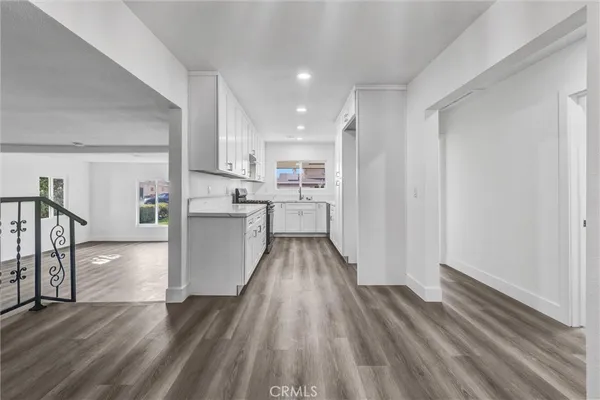 a view of a kitchen with wooden floor electronic appliances and stairs