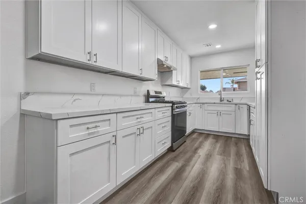 a kitchen with white cabinets appliances and sink