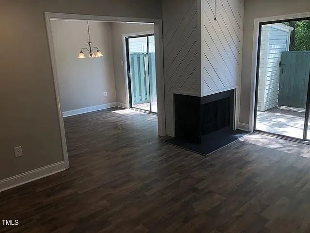 an empty room with wooden floor fireplace and windows
