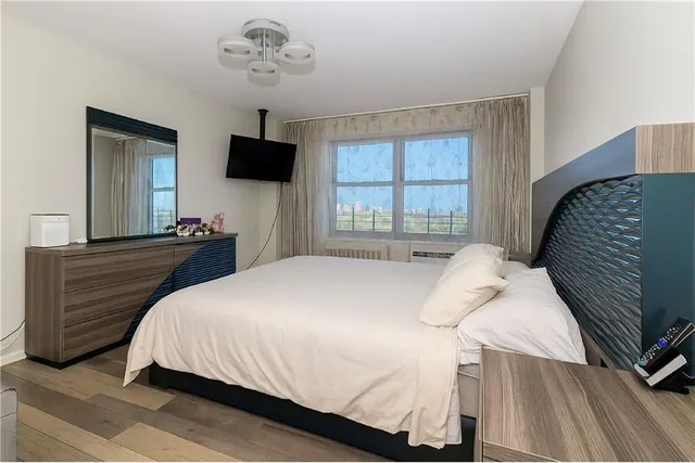 a bedroom with a bed and a flat tv screen on dresser