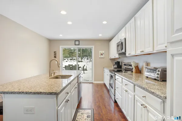 a kitchen with granite countertop a sink stove top oven and cabinets