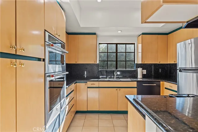 a kitchen with stainless steel appliances granite countertop a sink a stove and a refrigerator