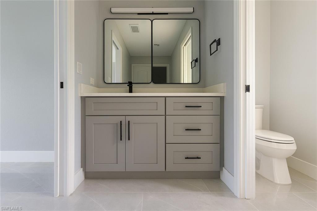 116 Ridgemont Drive Lehigh Acres, FL 33972 - Photo 26 of 45 a bathroom with a granite countertop toilet and a sink