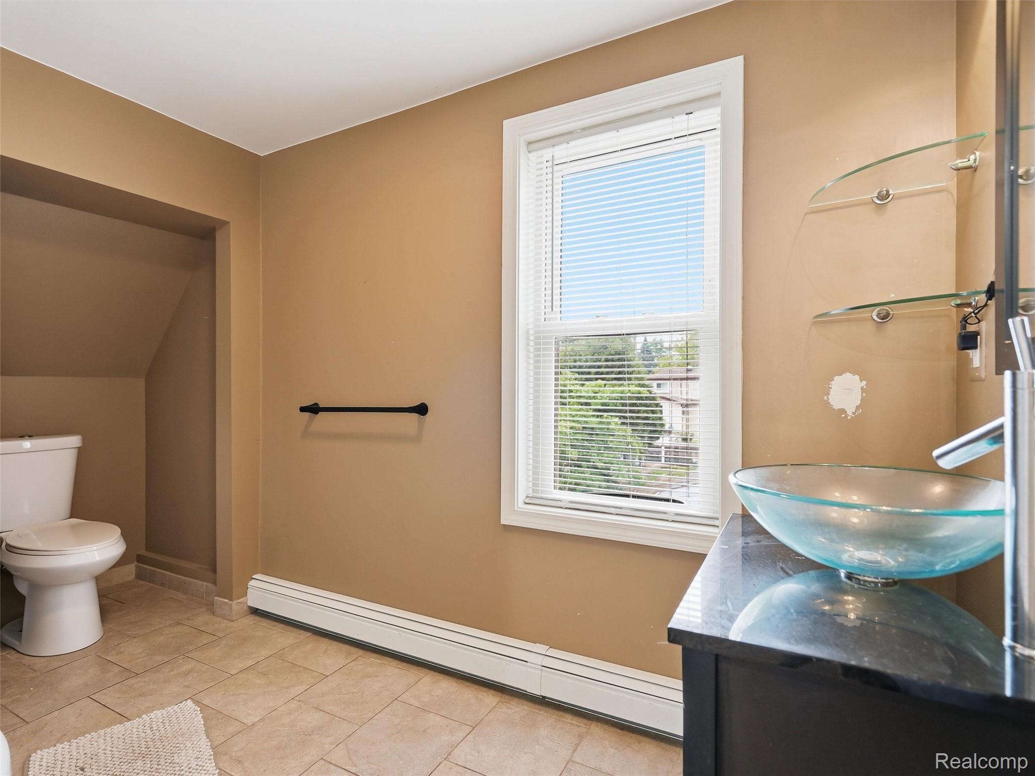 117 Kenyon Road Algonac, MI 48001 - Photo 32 of 47 Bathroom featuring a vessel sink with a dark vanity, glass shelving, a window with blinds, and tiled flooring