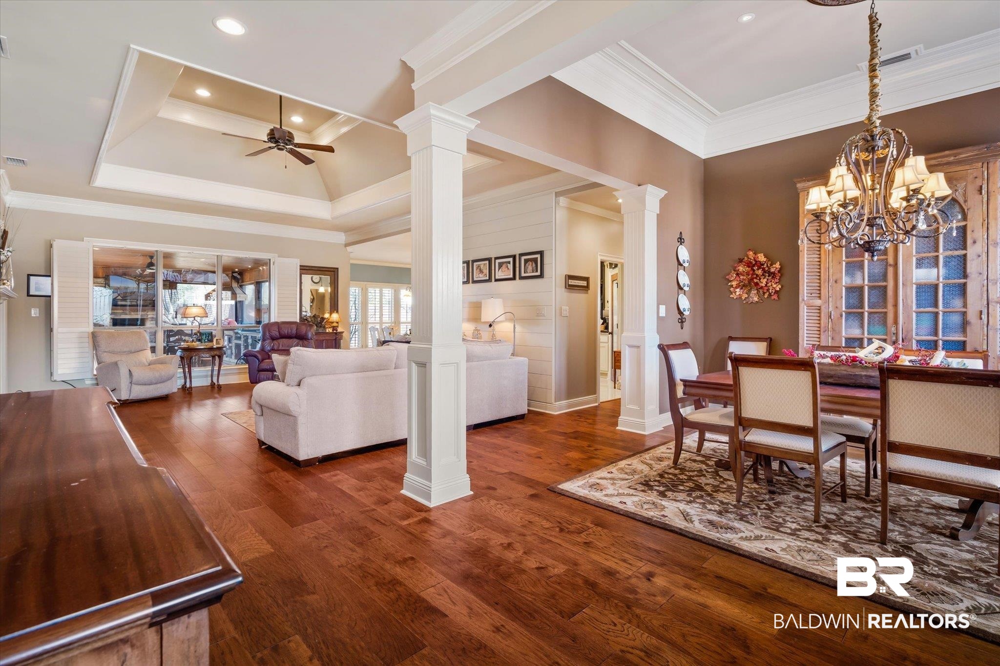5683 Spring Landing Drive Theodore, AL 36582 - Photo 4 of 49 Dining space featuring dark hardwood / wood-style floors, ceiling fan with notable chandelier, a tray ceiling, ornate columns, and ornamental molding