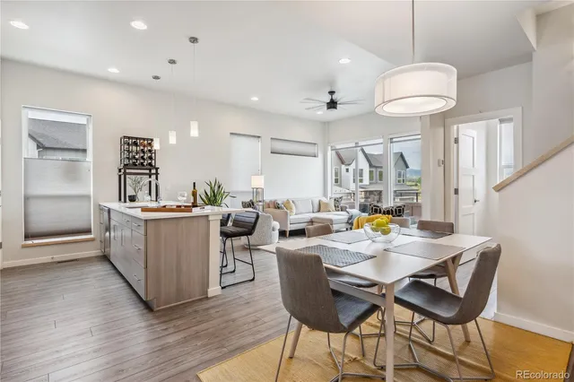 a kitchen with stainless steel appliances granite countertop a stove a sink a microwave a refrigerator a dining table and chairs with wooden floor