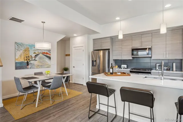 a kitchen with a dining table chairs refrigerator and microwave