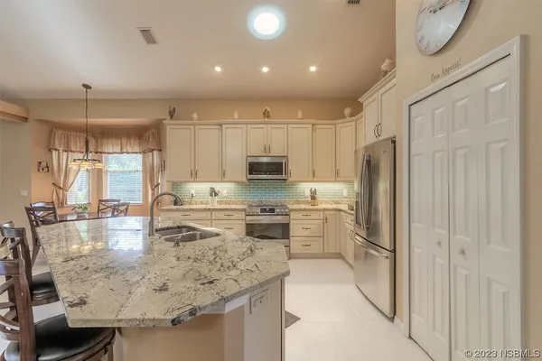 a kitchen with kitchen island a counter top space a sink stainless steel appliances and cabinets