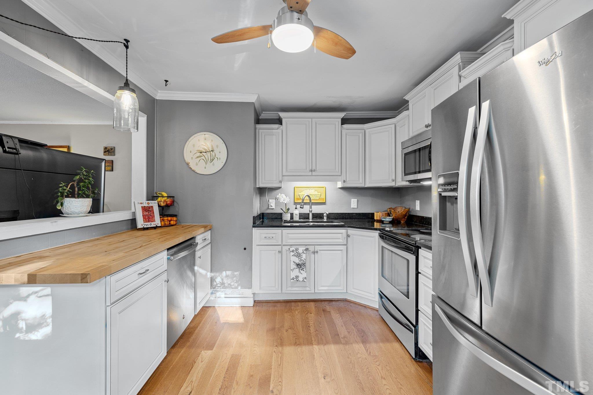 2615 Layden Street Raleigh, NC 27603 - Photo 8 of 34 a kitchen with granite countertop a refrigerator a stove a sink and dishwasher with wooden floor