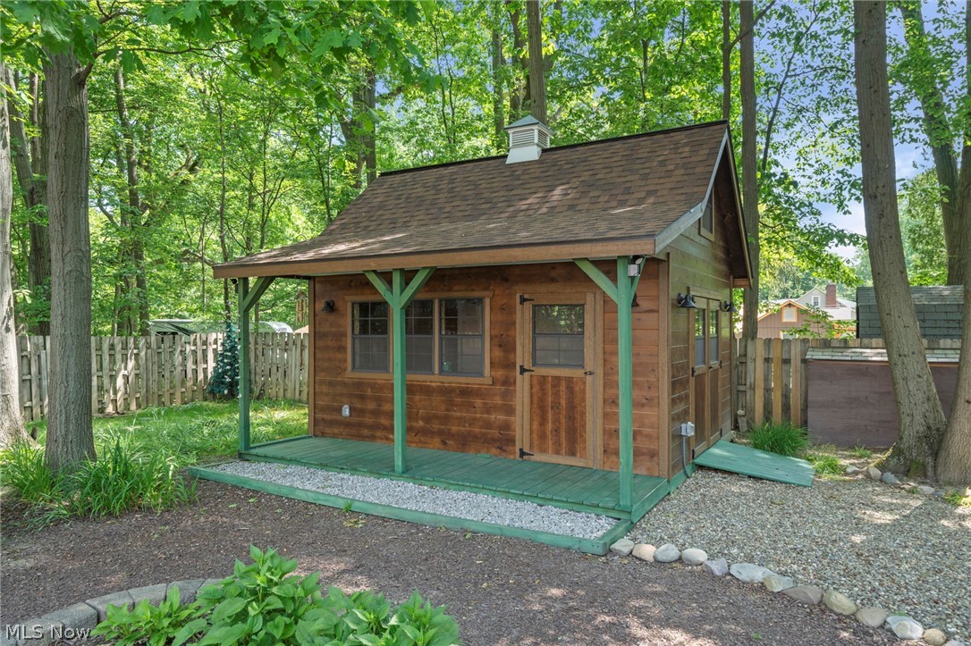 3871 Greentree Road Stow, OH 44224 - Photo 10 of 50 Wood-sided outbuilding featuring a covered porch with green-painted supports and decking, a shingled roof with a cupola, and a gravel perimeter