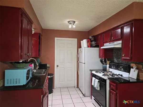 a kitchen with a refrigerator and a stove top oven