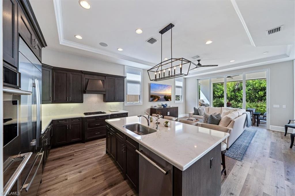 2139 Torino Way Naples, FL 34105 - Photo 7 of 24 a kitchen with stainless steel appliances granite countertop a sink a stove and a wooden floors