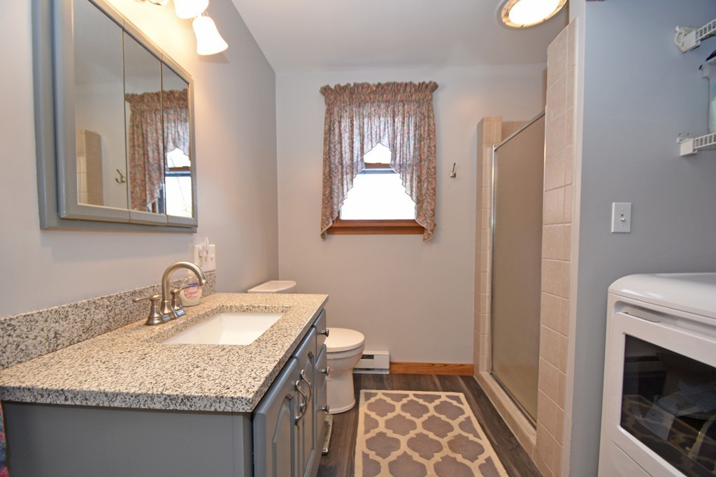 46 Davis Road, Unit B Millbury, MA 01527 - Photo 8 of 18 a bathroom with a granite countertop sink a mirror and a toilet