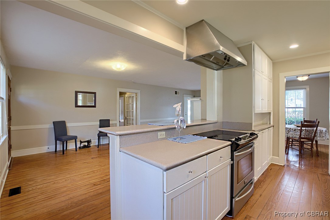 10371 Buckley Hall Road Mathews, VA 23109 - Photo 4 of 28 Kitchen featuring ventilation hood, stainless steel range with electric cooktop, white cabinets, and light wood finished floors