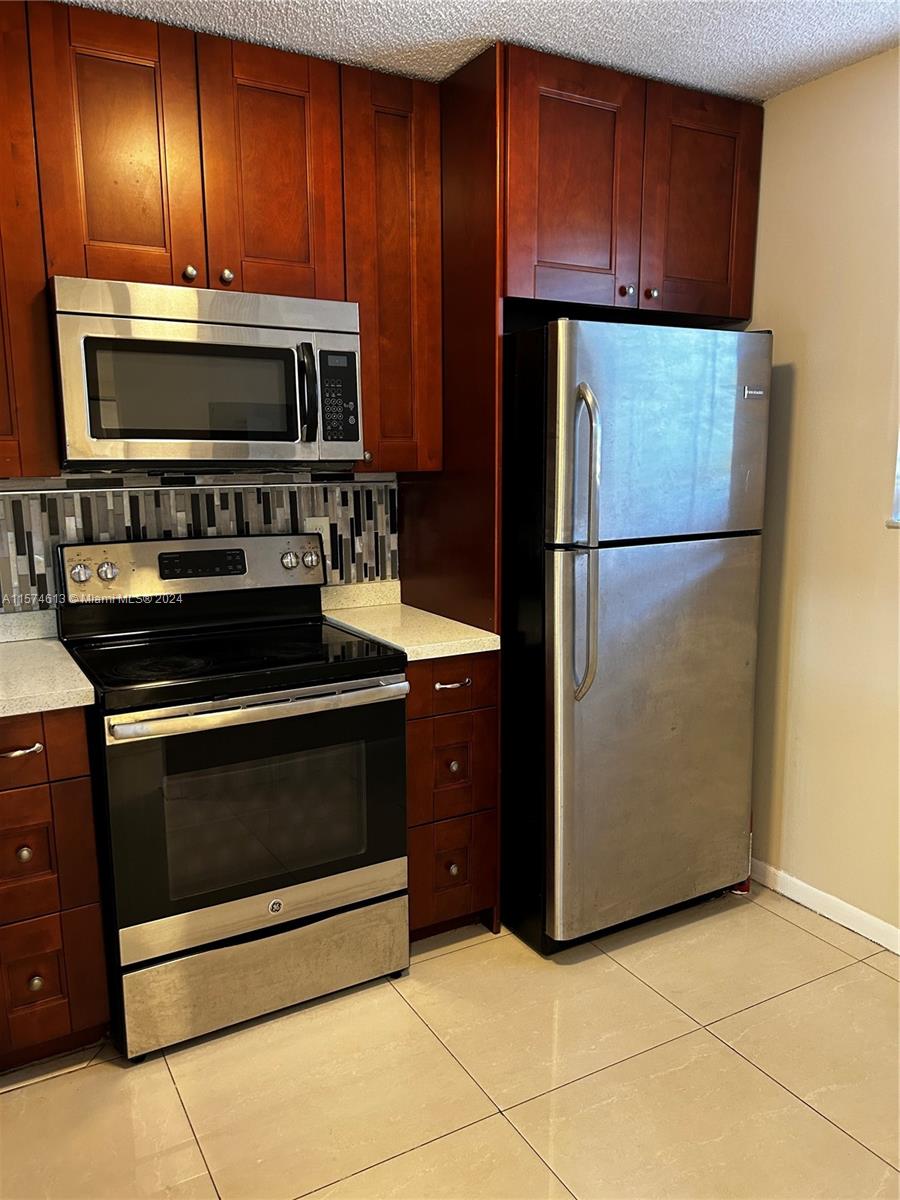 a kitchen with granite countertop stainless steel appliances and refrigerator