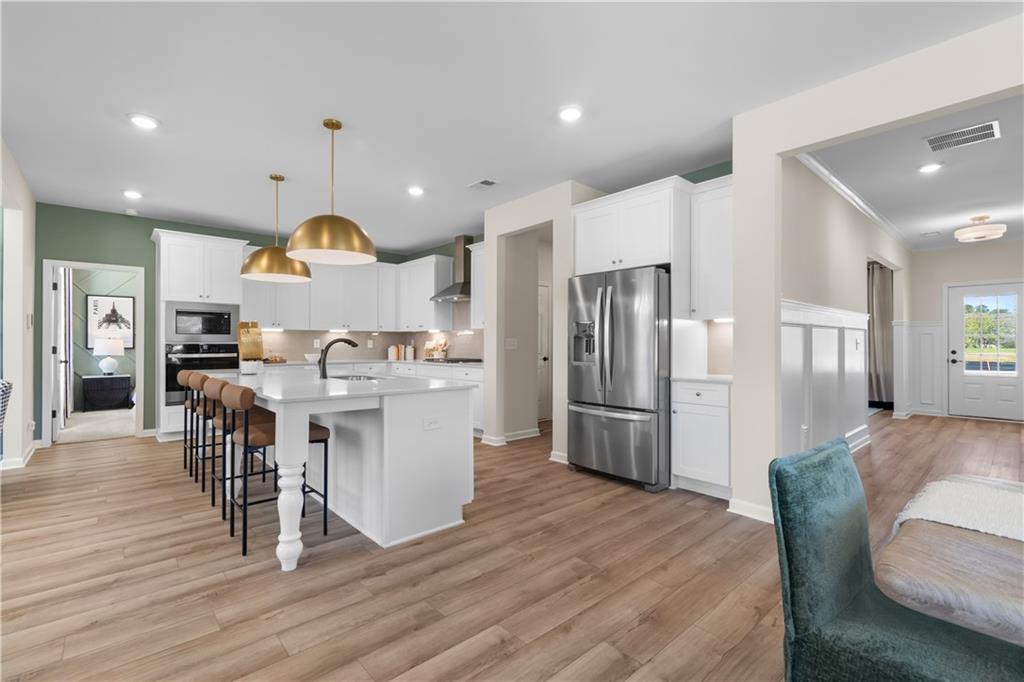 420 Hartsfield Road McDonough, GA 30252 - Photo 15 of 45 a kitchen with stainless steel appliances kitchen island granite countertop a refrigerator a stove a sink a dining table and chairs with wooden floor