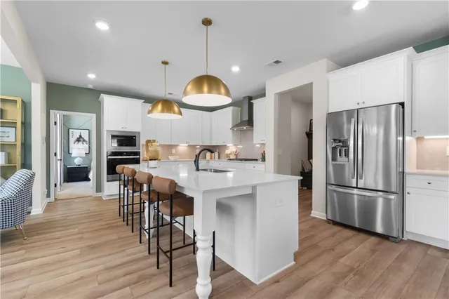 a kitchen with stainless steel appliances a dining table chairs refrigerator sink and cabinets
