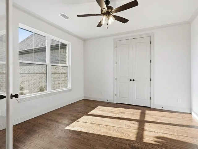 a view of an empty room with a window and wooden floor