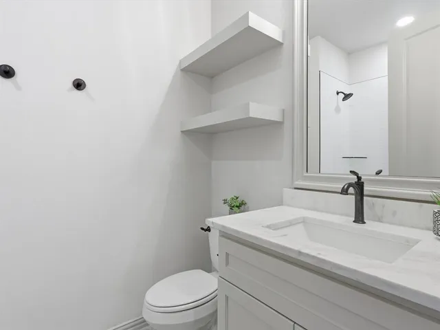 a bathroom with a granite countertop toilet a sink and a mirror