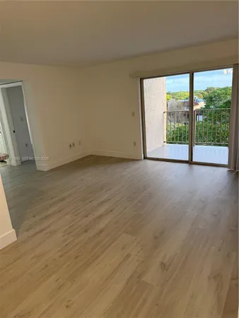 a view of a big room with wooden floor and windows