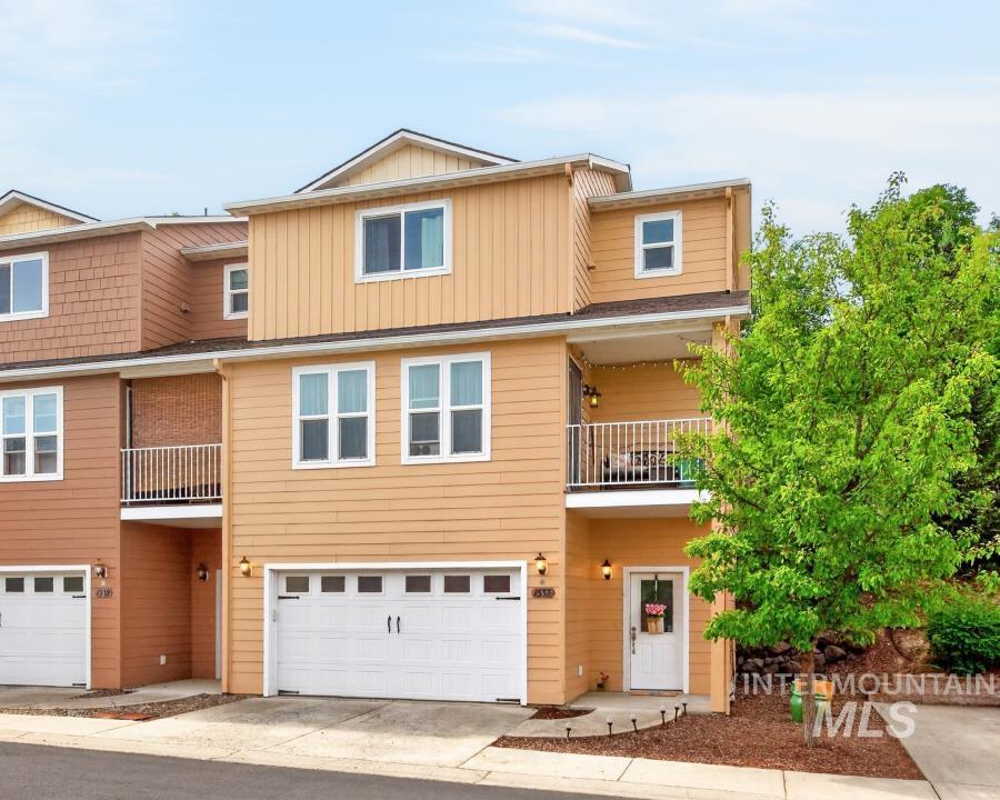 Multi-level townhouse exterior with light orange horizontal siding and white trim