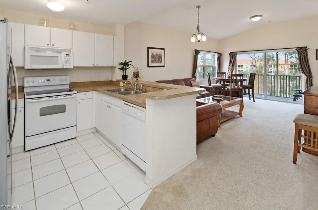 4510 Botanical Pl Circle, Unit 402 Naples, FL 34112 - Photo 2 of 15 a kitchen with kitchen island granite countertop a stove sink and cabinets