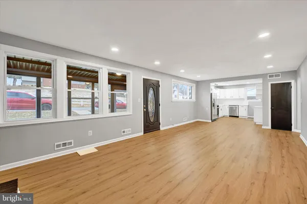 a view of an empty room with window and wooden floor